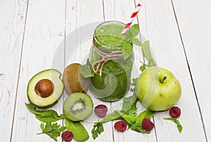 Healthy green smoothie with banana, spinach, avocado and kiwi in a glass bottles on a rustic