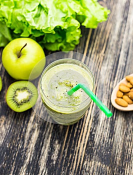 Healthy green smoothie with kiwi, apple on rustic wood background.