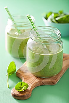 Healthy green spinach smoothie with mango banana in glass jar