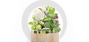 Healthy green vegan vegetarian food in full paper bag, vegetables and fruits on white background. Shopping food supermarket, raw