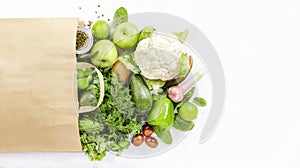 Healthy green vegan vegetarian food in full paper bag, vegetables and fruits on white background. Shopping food supermarket, raw