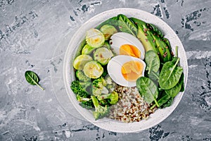 Healthy green vegetarian buddha bowl lunch with eggs, quinoa, spinach, avocado, grilled brussels sprouts and broccoli