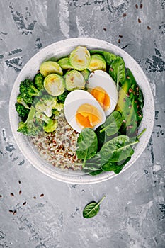 Healthy green vegetarian buddha bowl lunch with eggs, quinoa, spinach, avocado, grilled brussels sprouts and broccoli