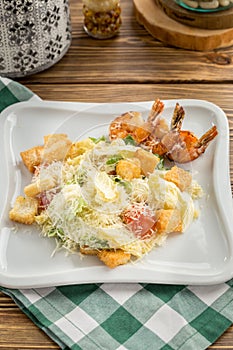 Healthy Grilled Caesar Salad with shrimp, parmesan Cheese and Croutons on wooden table