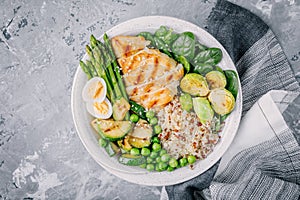 Healthy grilled vegetables buddha bowl with chicken and quinoa, spinach, egg, zucchini, asparagus, Brussels sprouts and green peas