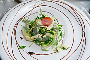 Healthy habbit of eating salad celery and apple arugula mix on a white flat plate decorated with balsamic sauce on a gray cloth photo