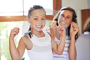 Healthy habits start from young. Portrait of an adorable little girl flossing her teeth with her mother at home.