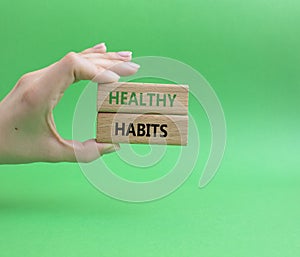 Healthy habits symbol. Concept word Healthy habits on wooden blocks. Businessman hand. Beautiful green background. Business and