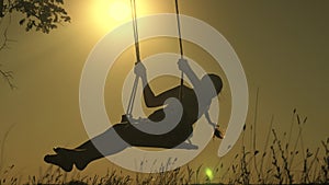 Healthy happy child rides on a rope swing on branch in park. little cheerful girl laughs, rejoices and waves her arms in