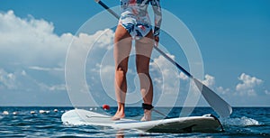 Healthy happy fit woman in bikini relaxing on a sup surfboard, floating on the clear turquoise sea water. Recreational