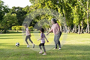 A healthy and happy grandmother with her granddaughter is playing football in the park