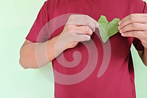 Healthy heart and love for nature and volunteer for environment concept. Young Asian man hands holding a green heart