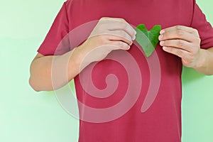 Healthy heart and love for nature and volunteer for environment concept. Young Asian man hands holding a green heart