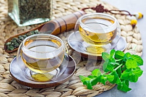 Healthy herbal mint tea in oriental cup with fresh peppermint and tea scoop on background, horizontal