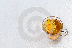 Healthy herbal tea with dandelions in a glass cup, ice and yellow dandelion flower inside on a white background