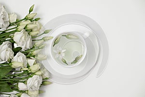 Healthy herbal tea in a white cup with Lisianthus flowers for relaxation and wellness