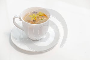 Healthy herbal tea in a white cup with medicinal herbs and flowers