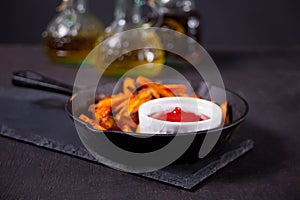 Healthy homemade baked sweet potato fries on the metal pan with dip tomatoes sauce