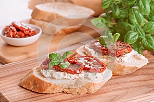 Healthy homemade breakfast concept. Delicious toasts with ricotta cheese, sun dried tomatoes with olive oil topped with basil