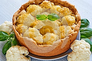 Healthy homemade cauliflower pie on the gray plate decorated with fresh basil leaves. Vegetarian cauliflower tart
