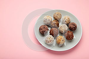 Healthy homemade energy balls with cranberries, nuts, dates and rolled oats on pink background. Space for text