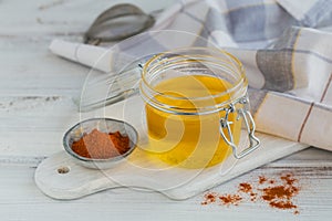 Healthy homemade Ghee or clarified butter in a jar and paprika powder on white wooden table. Healthy Ayurveda food