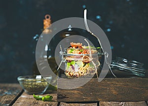 Healthy homemade jar quinoa salad with sun-dried tomatoes, avocado, basil