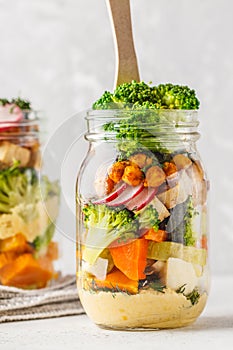 Healthy Homemade Mason Jar Salad with baked vegetables, hummus,