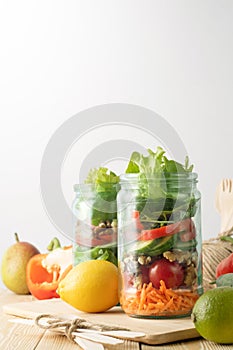 Healthy homemade mason jar salad with fresh pear tomatoes, carrots and herbs. Vegetarian concept