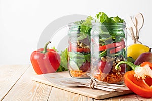 Healthy homemade mason jar salad with fresh pear tomatoes, carrots and herbs. Vegetarian concept