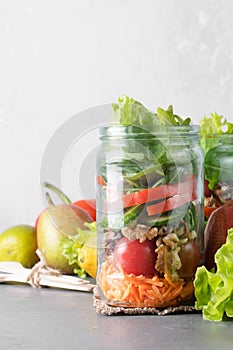 Healthy homemade mason jar salad with fresh pear tomatoes, carrots and herbs. Vegetarian concept