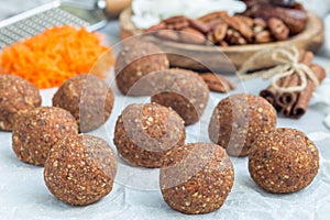 Healthy homemade paleo energy balls with carrot, nuts, dates and coconut flakes, on a parchment, horizontal