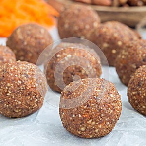 Healthy homemade paleo energy balls with carrot, nuts, dates and coconut flakes, on a parchment, square format
