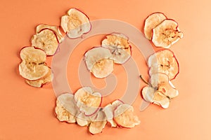 Healthy homemade pple chips are lying on coral background