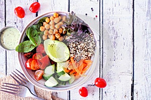 Healthy homemade salad bowl with avocado, chickpeas, quinoa and vegetables, table scene over white wood