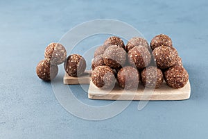 Healthy homemade sweets on a wooden cutting board. Energy balls are a healthy snack. Smooth balls on a blue background, place for