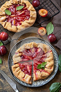 Healthy homemade wholegrain fruit pie, sweet crostata on a rustic table. Vegan vegetarian dessert, plums galette with almonds