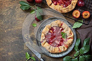 Healthy homemade wholegrain fruit pie, sweet crostata on a rustic table. Vegan vegetarian dessert, plums galette with almonds.