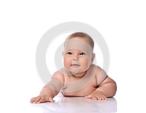 Healthy infant child baby girl kid in diaper is lying on her stomach holding arm outstretched, slapping on floor