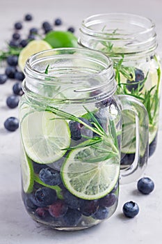 Healthy infused water with fresh blueberry, lime and rosemary, vertical