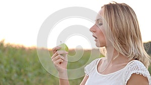 Healthy joyful young woman eating green apple and smiling