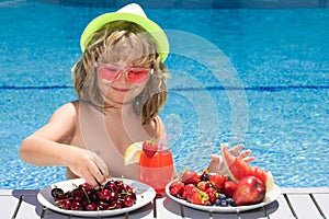 Healthy kids and summer vacation. Kid with fruits and juice smoothie cocktail in summer pool. Child on summer vacation
