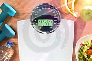 Healthy life concept with weighing scale with message and objects