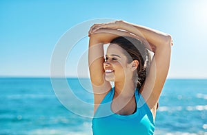 Because a healthy life is a happy life. a young woman stretching while out on the beach on a sunny day.