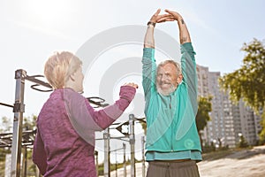 Healthy lifestyle. Beautiful senior or mature family couple in sportswear doing stretching exercises together in the