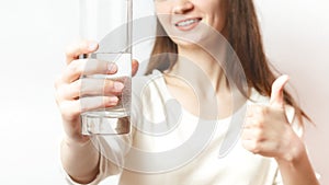 Healthy lifestyle. caucasian female hand holds glass of clear water give to camera smiling selective close up focus. Healthcare.