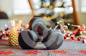 Healthy lifestyle during Christmas feasting period concept. Black dumbbells with Christmas ornaments.