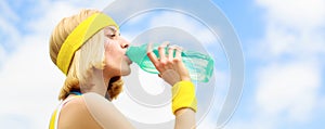 Healthy lifestyle concept. Drinking during sport. Young woman drinking water after run. Woman in sports wear is holding