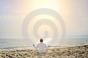 Healthy lifestyle concept - man doing yoga meditation exercises on the beach