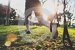 Healthy lifestyle concept.Muscular athlete exercising trx outside in sunny park.Great TRX workout.Young handsome man in